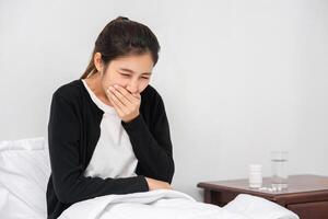 The woman coughed and covered her mouth with her hand and sat on the bed. photo