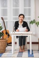 A woman sitting happily at the desk analyzes documents. photo