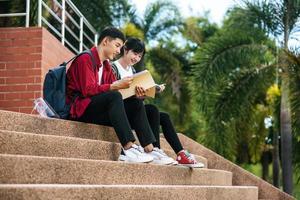 estudiantes masculinos y femeninos sentados y leyendo libros en las escaleras. foto