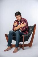 The man in a striped shirt sits sick and sits on a chair and crosses his arms. photo