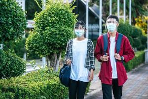 estudiantes masculinos y femeninos usan frío facial y máscaras caminan por el sendero foto