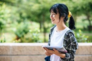 Female students stand on the stairs and hold books. photo