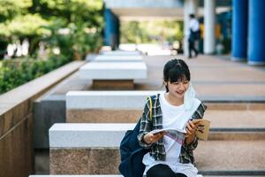 Female student sitting on the stairs and read a book. photo