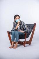 An uncomfortable woman sitting on a chair and wearing a mask