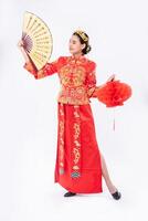 mujer usa traje cheongsam promueve el abanico chino y la lámpara roja en el gran evento del año nuevo chino foto