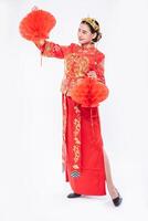 mujer vistiendo traje cheongsam mostrar decorar la lámpara roja a su tienda en el año nuevo chino foto