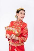 Mujer vistiendo traje cheongsam sonríe para obtener dinero de regalo de un pariente en el año nuevo chino foto