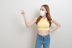 portrait beautiful woman wearing mask with hand presenting or pointing photo