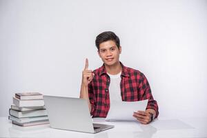 A man using a laptop in the office and doing a document analysis. photo