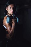 A young beautiful woman with weights for arm strengthening. photo