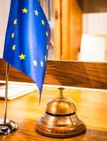 Front desk with europe union flag and protective shield dueto pandemic. Hospitality business legislation and travel industry. Vertical background blank space.