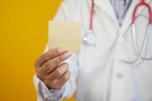 doctor hand hold a sticky note against yellow background photo