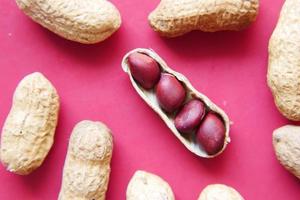 Processed pea nuts on red background close up photo