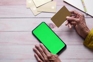 senior women hand holding credit card and using smart phone shopping online photo