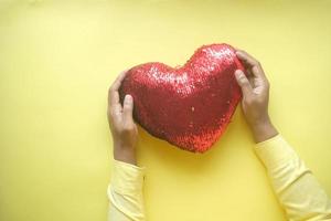 man holding big red heart on yellow background photo