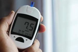 man's hand measuring blood sugar level at home photo