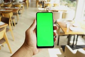 Cerca de la mano del hombre joven con un teléfono inteligente con pantalla verde foto