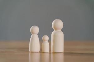 wooden figures peg doll of family members on wood table, Family relationship, family home, foster care, homeless charity support concept, family mental health, international day of families. photo