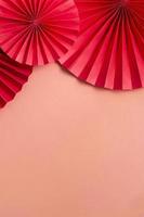 Red paper fans on a pink background copy space. Vertical format photo