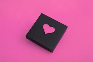 Gift black box with hearts on a pink background. Closeup copy space photo