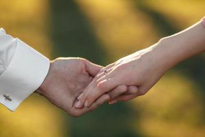 young couple holding hands on the arm ring. Close Up view photo