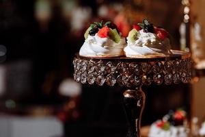 postres de crema con frutos rojos en barra de chocolate. mesa con dulces y golosinas para la recepción de la boda o fiesta de cumpleaños, decoración de mesa de postres. deliciosos dulces en buffet de dulces. enfoque selectivo foto