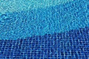 Los cáusticos del fondo del mosaico de la piscina se ondulan como el agua del mar. fluir con olas, deporte y concepto de relajación. fondo de verano. textura de la superficie del agua. vista superior. ondas de agua con foto