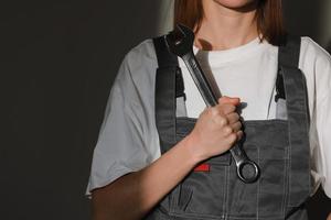 Retrato de hermosas trabajadoras de la construcción con ropa protectora, casco naranja, llave de sujeción de mano llave de tornillo grande con luz solar foto