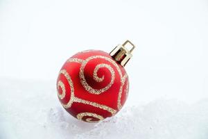 bola de Navidad de brillo rojo sobre la nieve blanca. foto