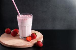 Milkshake with strawberries on black background. photo