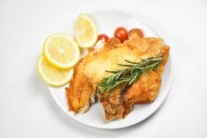fried fish fillet sliced for steak or salad cooking food with herbs spices rosemary and lemon tilapia fillet fish crispy served on white plate