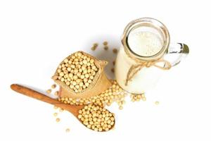 Soy milk in glass jar for healthy diet and natural bean protein - Soybean on wooden spoon and dried soy beans in the sack isolated on white background photo