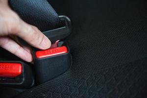cinturón de seguridad del automóvil mientras está sentado dentro del automóvil antes de conducir y emprenda un viaje seguro: la mano abrocha el cinturón de seguridad del automóvil