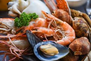 Cooked steamer food served seafood buffet concept - Fresh shrimps prawns squid mussels spotted babylon shellfish crab and seafood sauce lemon on plate background photo