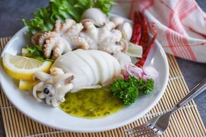 Ensalada de calamar especias salsa de chile limón ajo servido sobre fondo de placa blanca - comida cocida calamares pulpo o sepia en un restaurante de mariscos