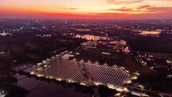 Vista aérea de una granja solar que produce energía limpia durante la noche con crepúsculo. visible en todo el área