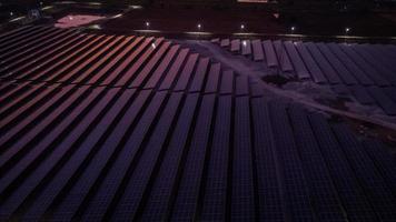 Vista aérea de una granja solar que produce energía limpia durante la noche con crepúsculo y visible en todo el área. foto