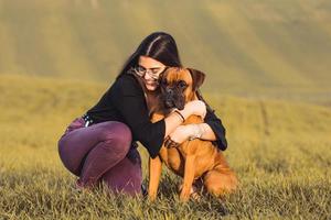 chica de moda con su perro boxer en la pradera en otoño foto
