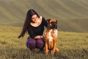 chica de moda con su perro boxer en la pradera en otoño foto