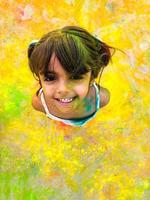 Laughing girl with paint stained her face. Child laughs happily enjoying active games and creativity. Head thrown back, top view, copy space for your text. Back to school photo