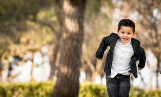 Fashion little boy jumping and wearing a leather jacket. Park or forest, outdoor