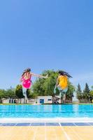 Two young girls jumping into the pool. Summer begins concept. Copy space photo