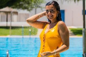 Mujer joven duchándose antes de bañarse en la piscina foto