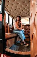 A vertical shot of a caucasian girl sitting inside a compartment with leather seats photo