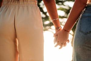 joven pareja de lesbianas tomados de la mano caminando al atardecer foto