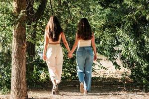 joven pareja de lesbianas tomados de la mano caminando al atardecer foto