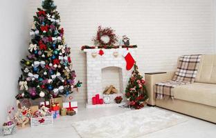 Decoración navideña de sala de estar elegante y luminosa con sofá vintage, chimenea, árbol de Navidad y velas rojas, concepto de año nuevo foto