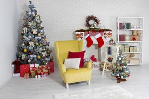 sillón amarillo navideño, árbol de navidad y chimenea en el interior foto