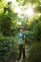 un niño con una mochila camina por el bosque. foto
