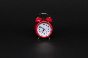red alarm clock on black background, isolated photo